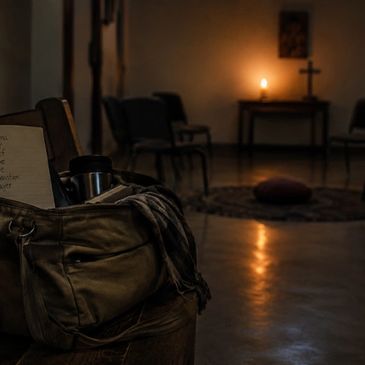 Dimly lit room with a candle, chairs, and a bag in the foreground.