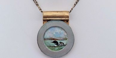 Round pendant necklace with a painted landscape inside.