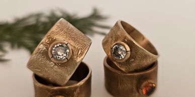 Two gold rings with intricate designs and sparkling gemstones.