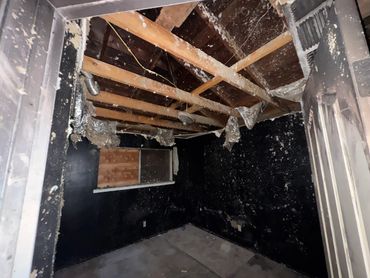 A room severely damaged by fire with charred walls and exposed ceiling beams.