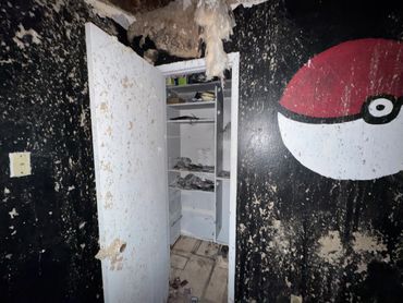 A room with a large Pokéball painting, showing severe water damage and mold.