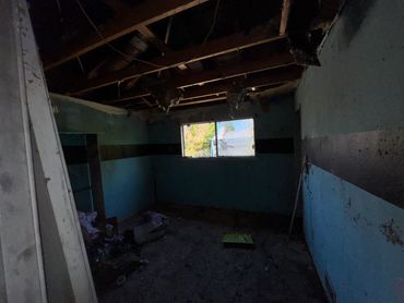 Dark, abandoned room with a broken roof and scattered debris.