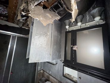 Severely damaged room with broken ceiling and scattered debris.