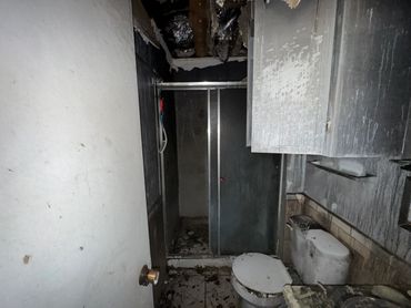 Abandoned bathroom with dirty toilet and damaged ceiling.