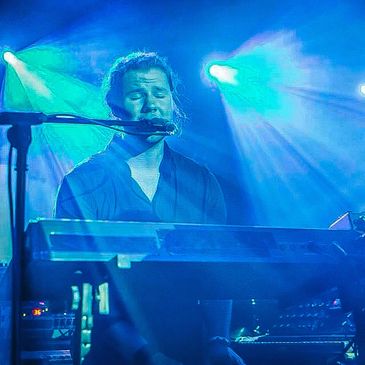 Alex Stokes performing and singing live on stage.