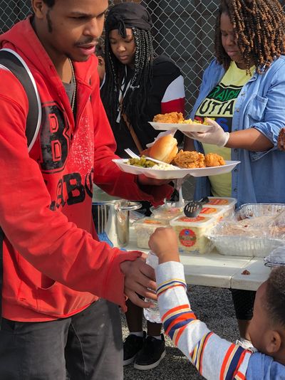 Man serving food to a child at an outdoor event.