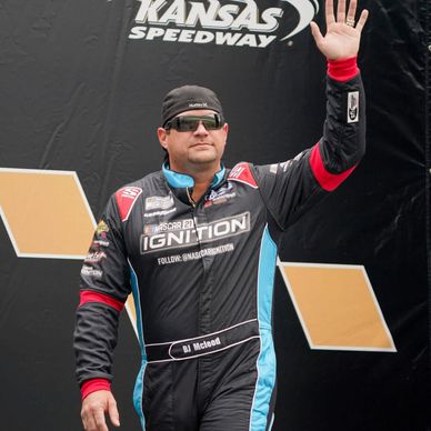 Race car driver BJ McLeod waves at Kansas Speedway event.
