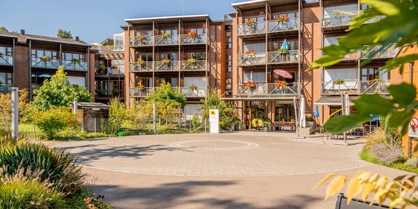 Moderner Wohnkomplex mit begrünten Balkonen und Innenhof.