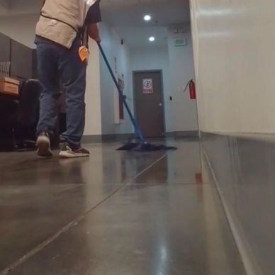 Persona limpiando un pasillo interior.