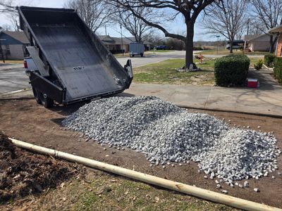Dump truck unloading gravel onto a prepared yard area for landscaping.