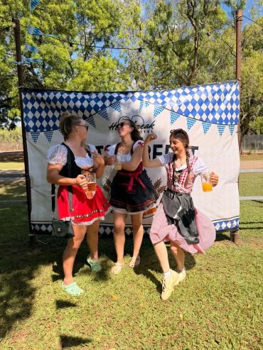 Three women in traditional dresses enjoying drinks outdoors.