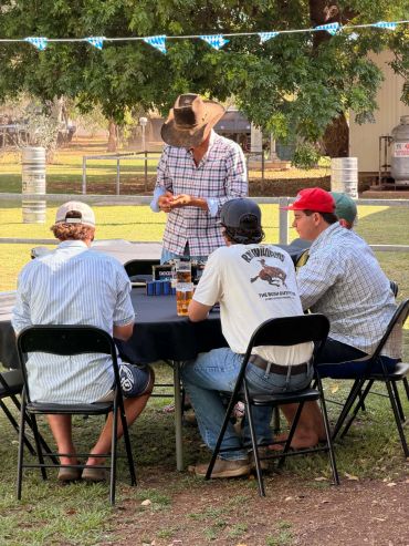 Group of men sitting and socializing outdoors under a tree.