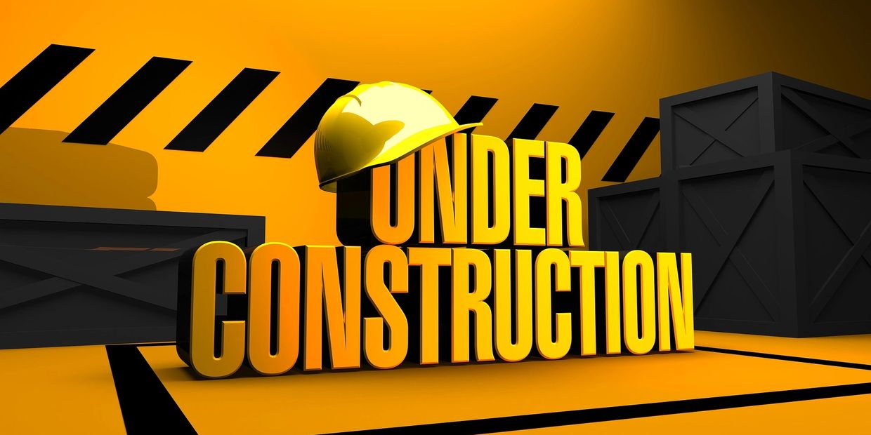 Yellow "Under Construction" sign with a hard hat and black crates.