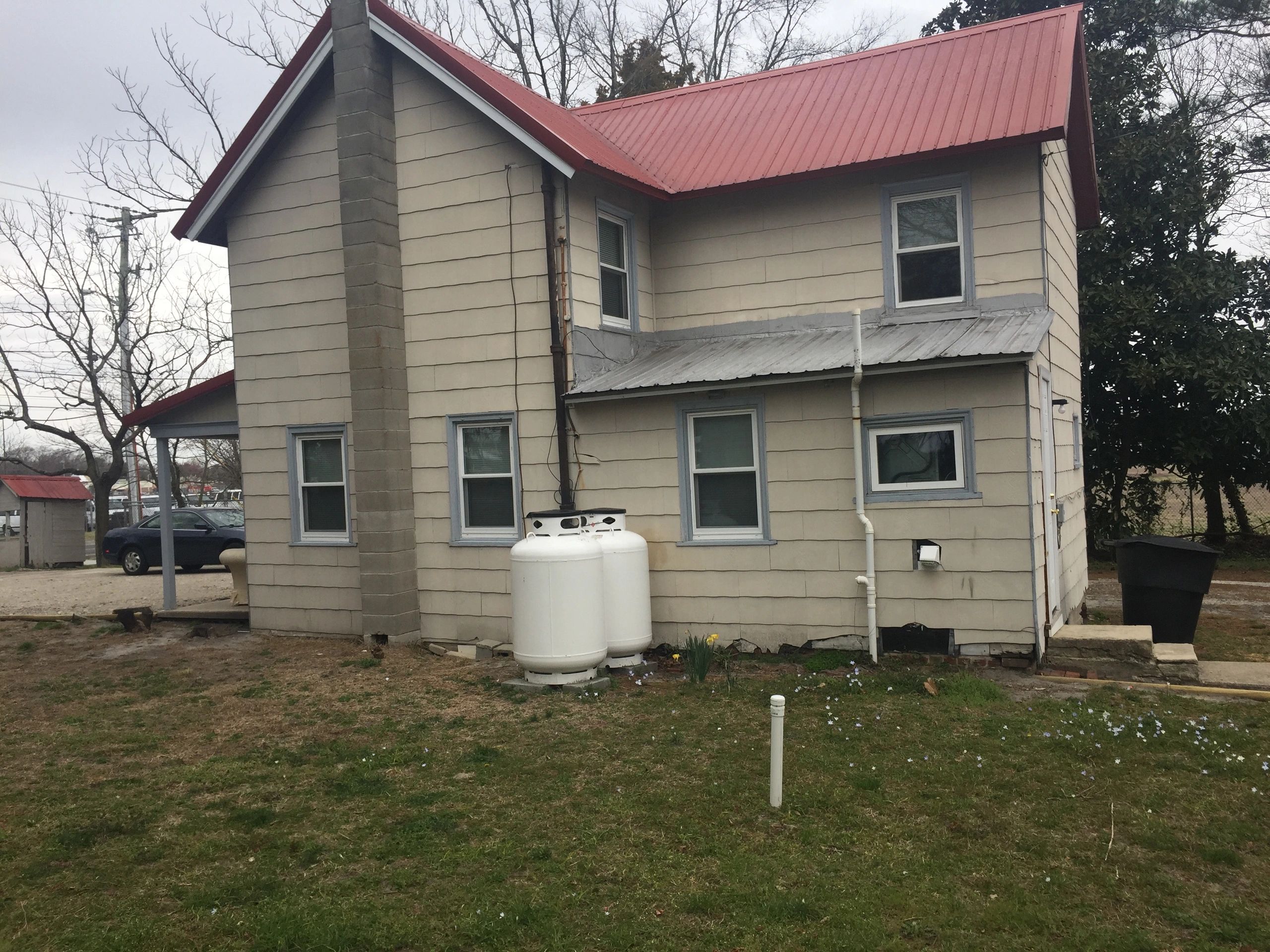 Old house with red roof and propane tanks outside.