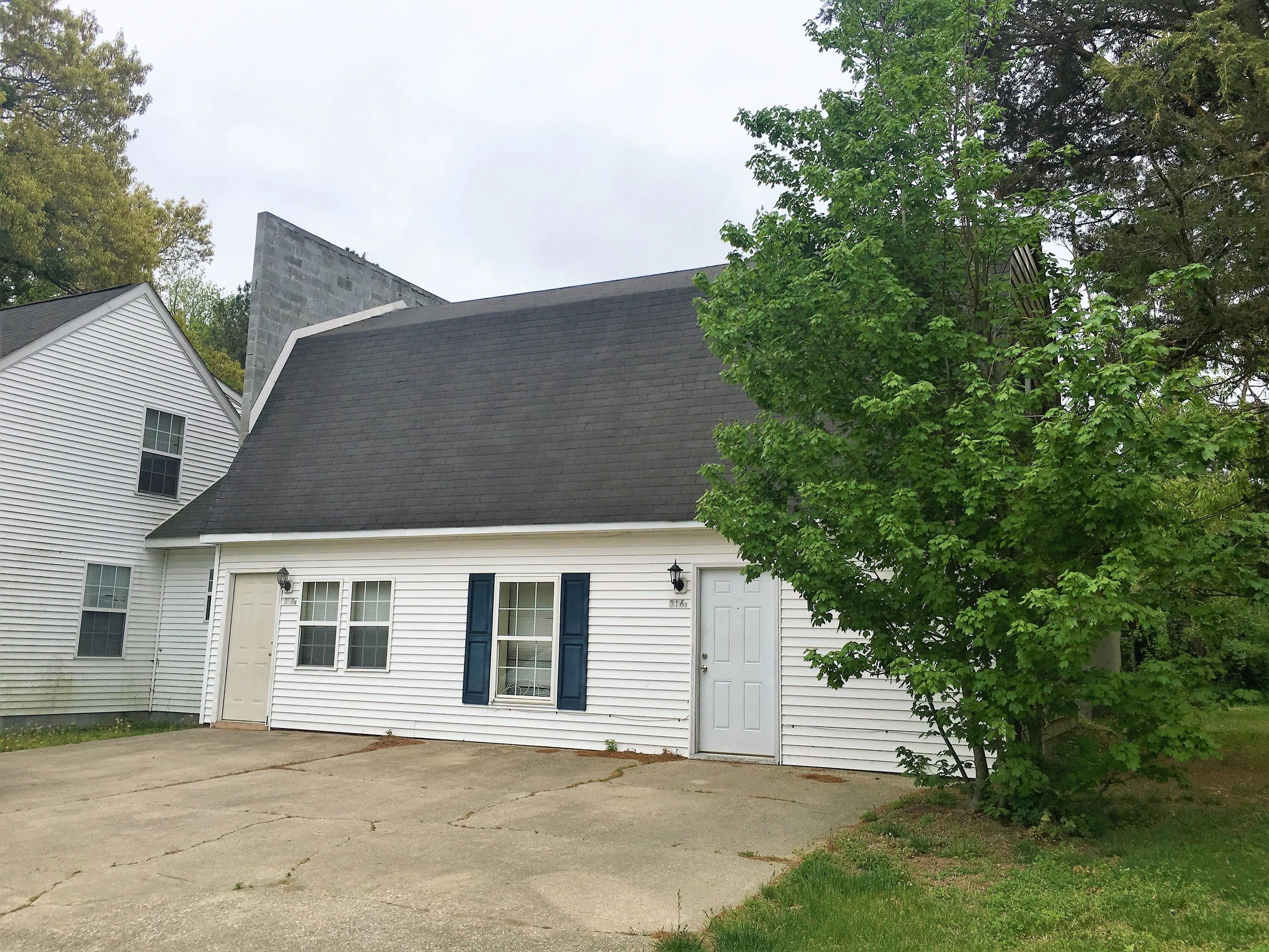A suburban house with a steep roof and green trees.