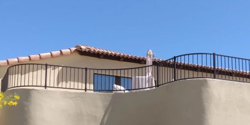 Balcony with railing and umbrella under clear blue sky.