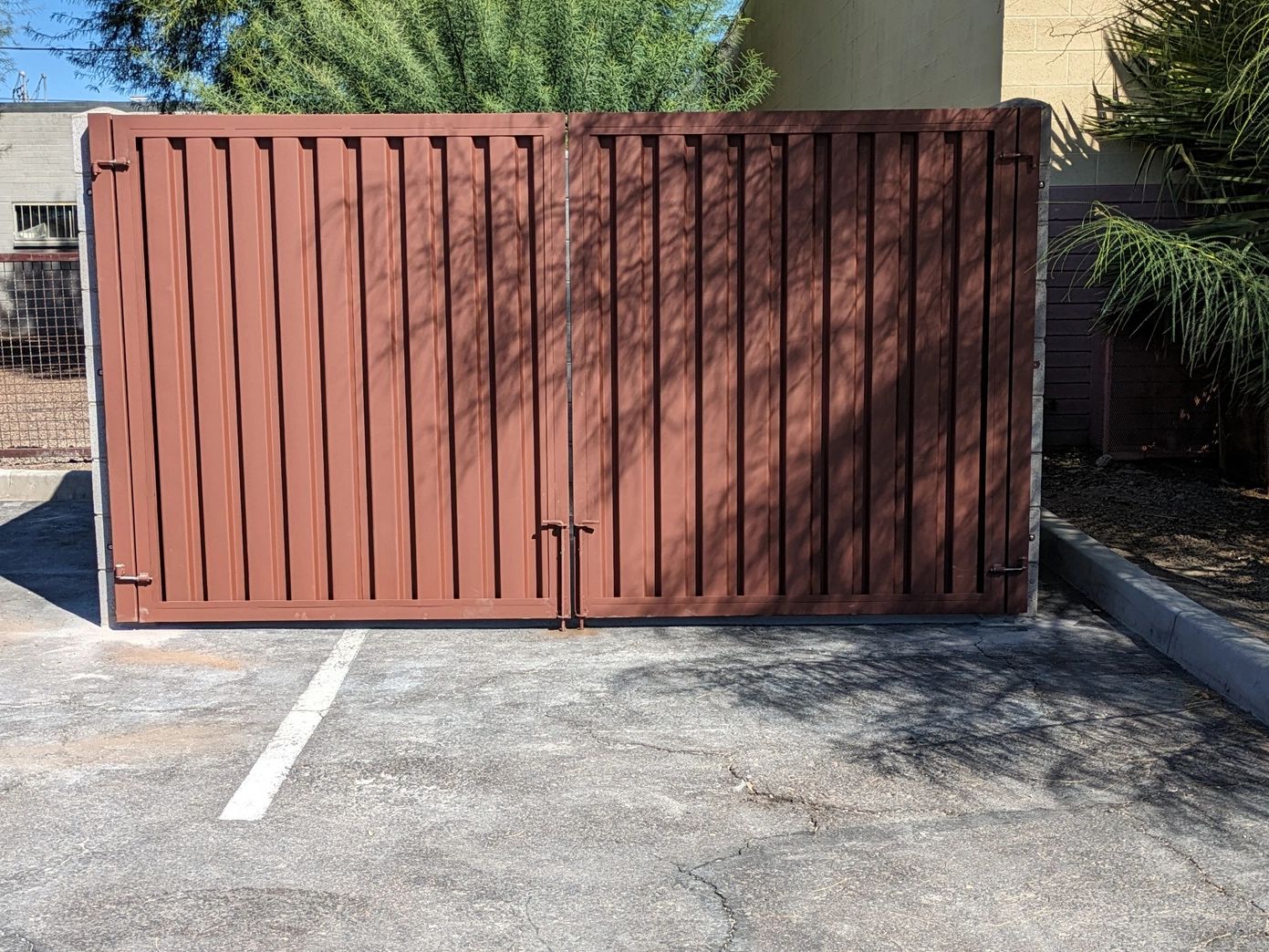 Closed rust-colored metal gate in a parking lot.