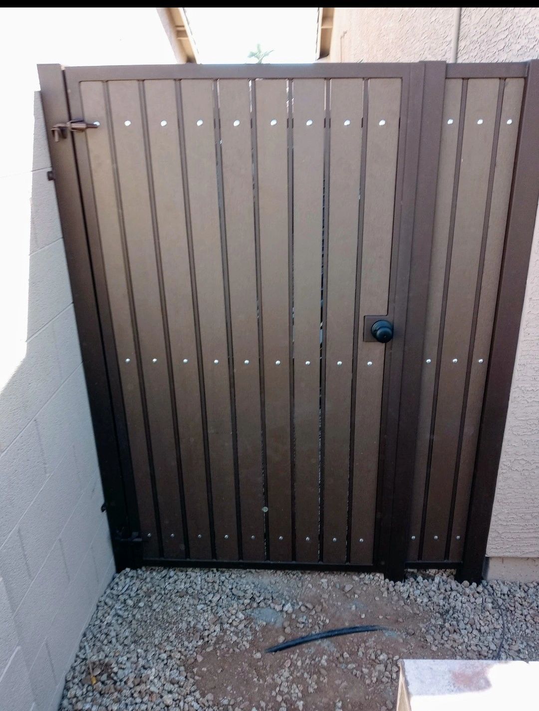 HOA-compliant composite wood trash can enclosure gate conceals trash and recycling bins. 