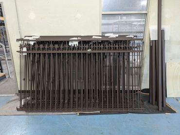 Fresh powder-coated custom spear top fence in rust brown texture. Ready for installation.