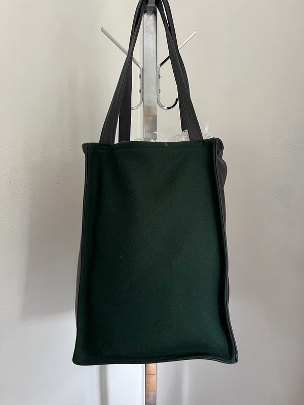 Simple black tote bag hanging on a metal stand.