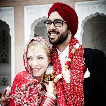 Fusion wedding for bride and groom wearing red and gold at sikh temple.