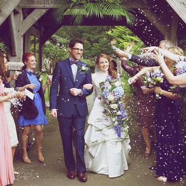 Bride holding long cascading vintage style wedding bouquet with blue flowers and greenery.
