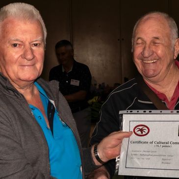 Two elderly men holding a certificate, smiling warmly.