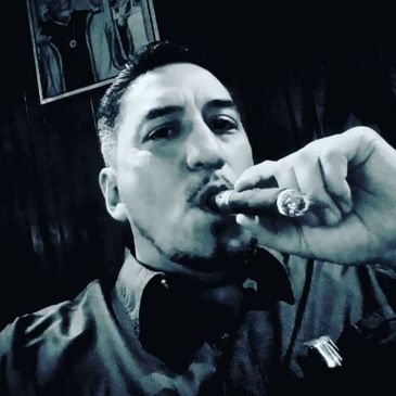 Man smoking a cigar in a dimly lit room.