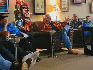 A group of men sitting and talking in a cozy room with festive decorations.