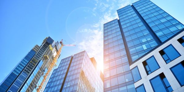 Modern glass skyscrapers under a bright blue sky with sunlight.