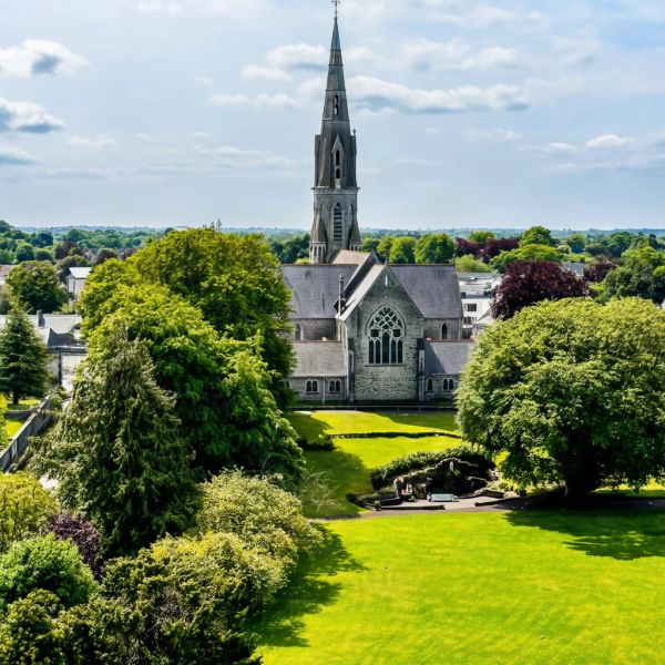 A church with a tall spire surrounded by greenery.