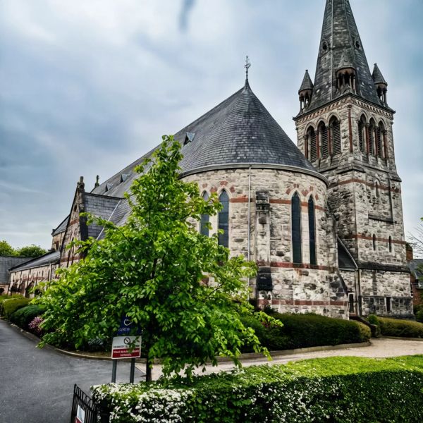Historic stone church with tall steeple on a cloudy day.