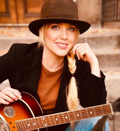 Smiling woman in a hat with guitar.