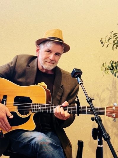 Man playing acoustic guitar with a microphone in front.