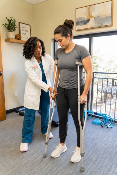 Dr. Dei teaching a patient how to use crutches safely after a car accident at her Orlando physical t