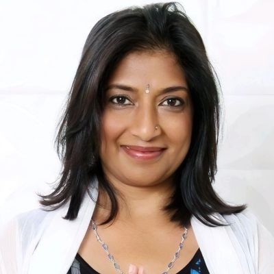 Smiling woman with medium-length black hair and a small bindi on her forehead.