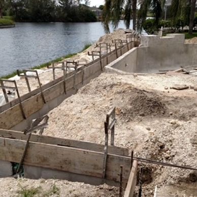 Construction site near water with wooden frames and concrete.
