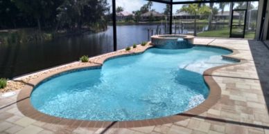 Backyard pool with hot tub overlooking a waterway.