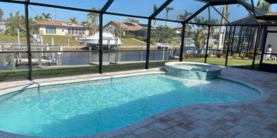 Pool with spa in a screened patio by a canal.