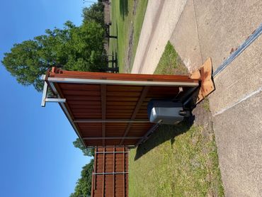 A brown wooden gate with an automatic opener on a sunny day.