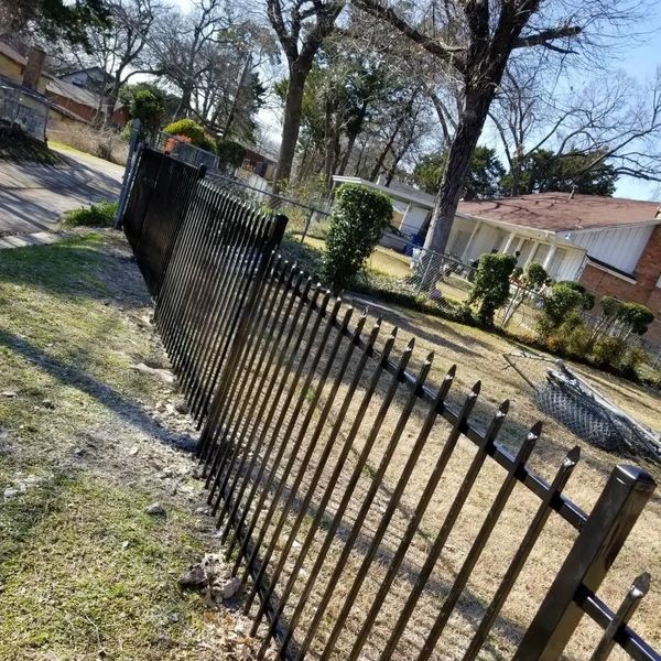 A black metal fence leaning unevenly in a residential yard.