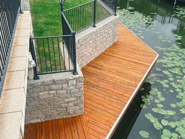 stained wood dock built into a limestone wall, overlooking a quiet canal lined with lily pads.