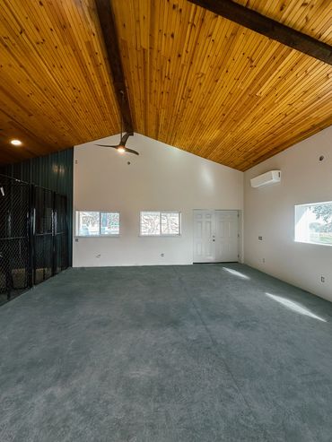 Barn with wood ceiling, exposed beams, and dog kennels with metal fencing for indoor outdoor use.