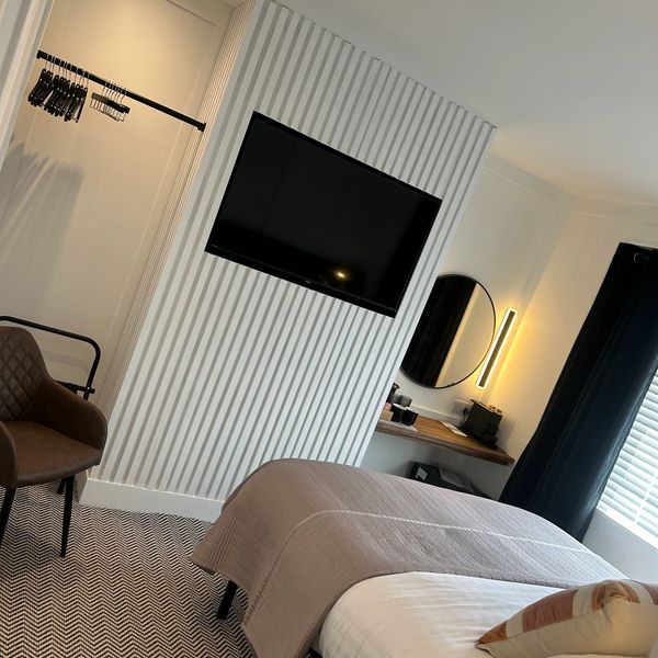 Modern bedroom with mounted TV and cozy bed.
