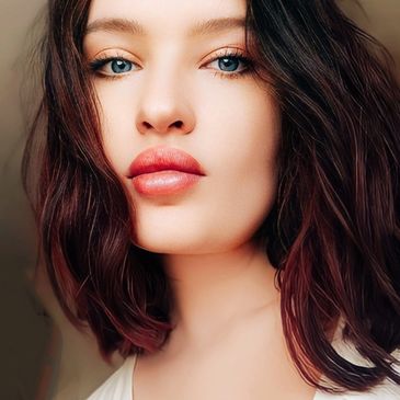 Close-up portrait of a woman with blue eyes and dark wavy hair.