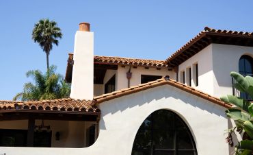 Mediterranean-style house with tile roof and palm trees.