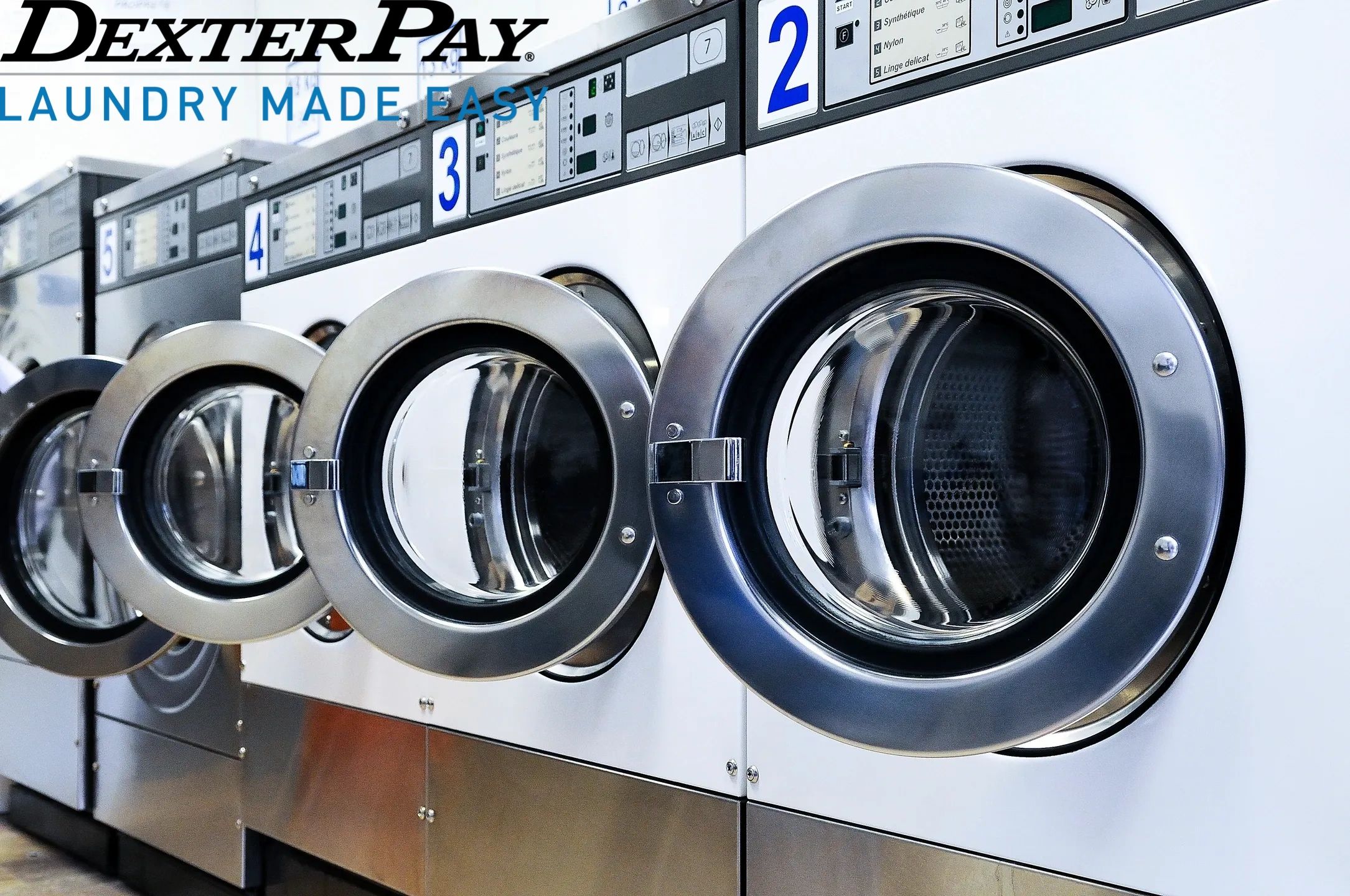 Row of open front-loading washing machines in a laundromat.