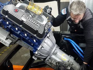 Mechanic installing a new COBRA engine and transmission.