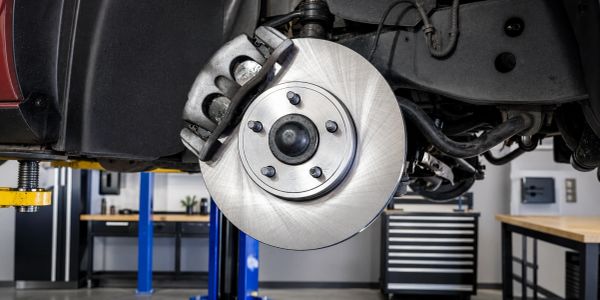 Close-up of a car brake disc and caliper in a workshop.