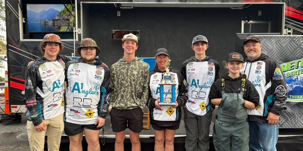 A group of anglers posing with a trophy at a fishing event.